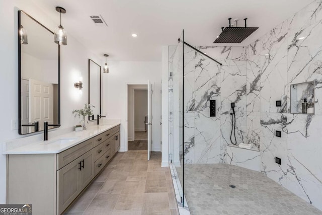 full bath featuring a marble finish shower, double vanity, a sink, and visible vents