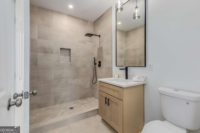 full bathroom featuring vanity, a tile shower, toilet, and recessed lighting