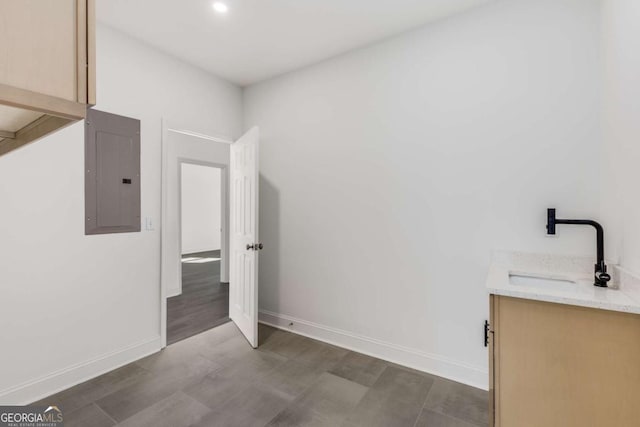 laundry room featuring dark wood-style floors, electric panel, baseboards, and a sink