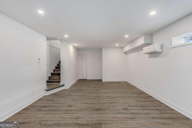 below grade area featuring baseboards, stairway, wood finished floors, a wall mounted air conditioner, and recessed lighting