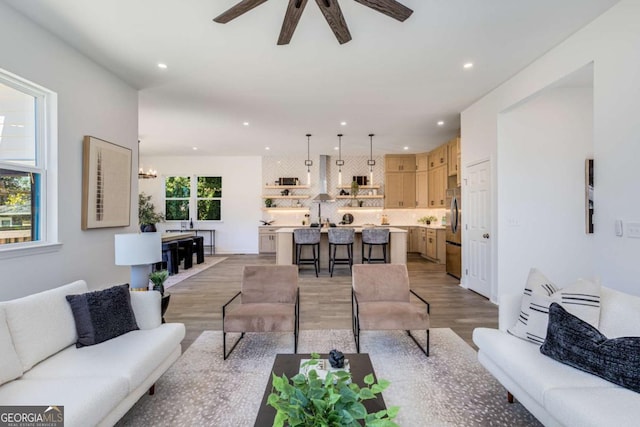 living area featuring ceiling fan with notable chandelier, light wood-style flooring, and recessed lighting