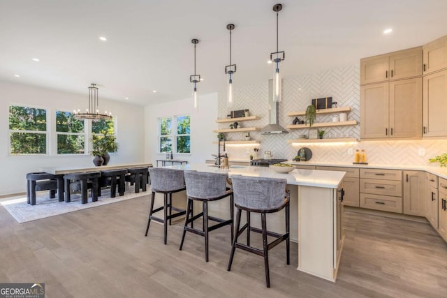 kitchen with light wood-style flooring, light countertops, backsplash, open shelves, and a center island with sink