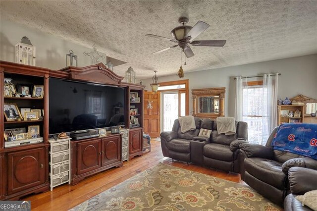 living room featuring a wood stove, hardwood / wood-style flooring, baseboards, and a textured ceiling