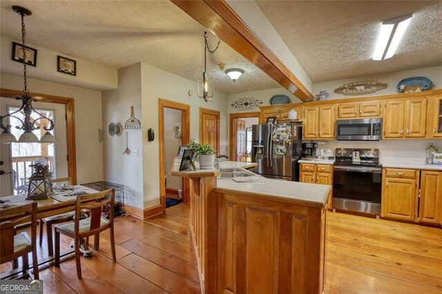 living area featuring light wood-type flooring, a wood stove, ceiling fan, and a textured ceiling