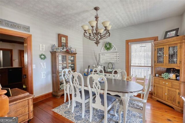 dining area featuring baseboards, light wood-type flooring, and a notable chandelier