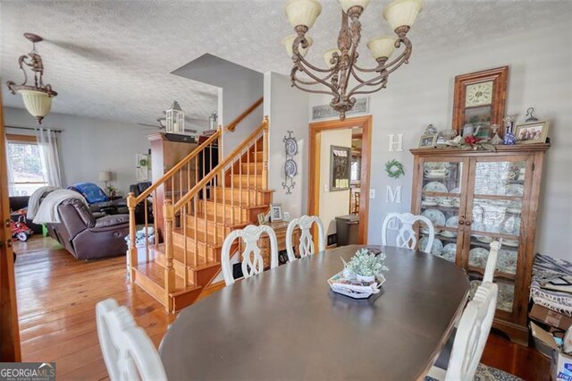 dining space with baseboards, a textured ceiling, light wood finished floors, and an inviting chandelier