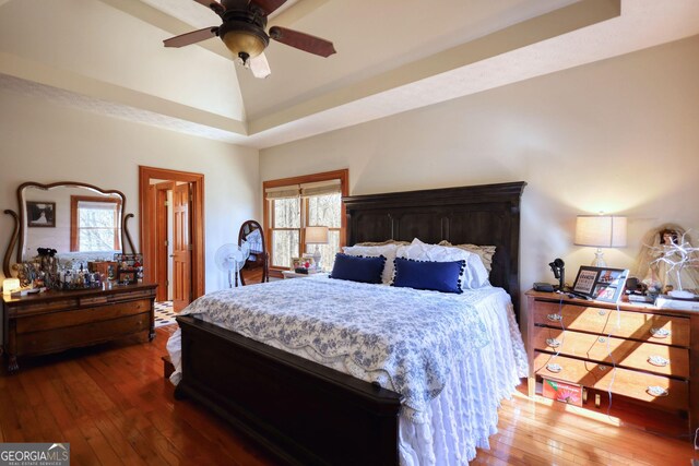 bedroom with baseboards, a raised ceiling, and dark wood-type flooring