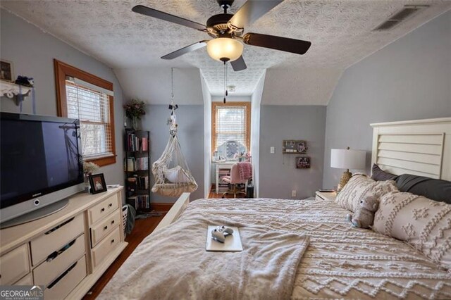 bedroom with lofted ceiling, a textured ceiling, baseboards, and wood finished floors