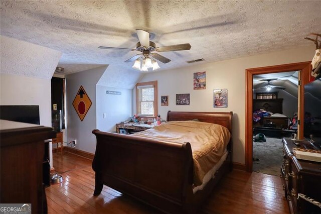 bedroom featuring lofted ceiling, hardwood / wood-style flooring, visible vents, and a textured ceiling