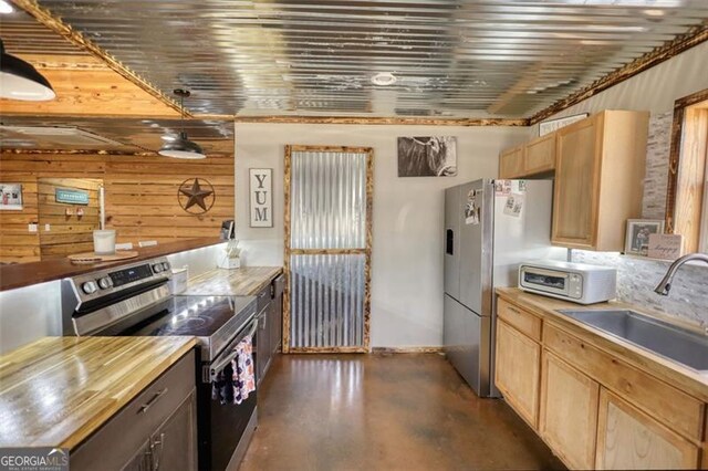 kitchen featuring dishwasher, stainless steel refrigerator, concrete flooring, light brown cabinets, and a sink