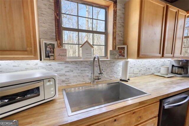 kitchen with finished concrete flooring, a toaster, stainless steel appliances, light brown cabinetry, and a sink