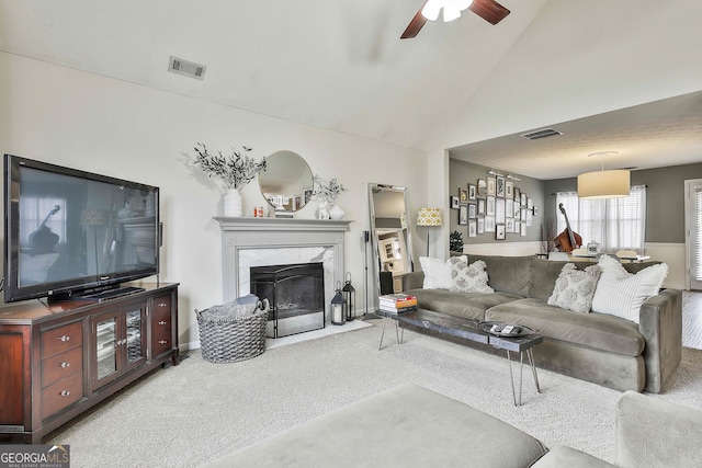 living area featuring carpet floors, a high end fireplace, visible vents, and high vaulted ceiling