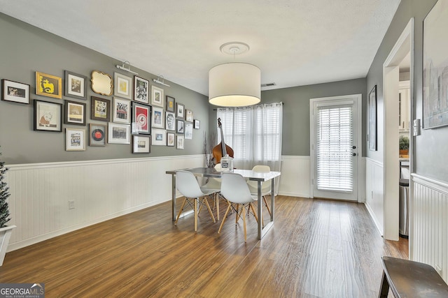 dining room featuring a wainscoted wall, a textured ceiling, and wood finished floors