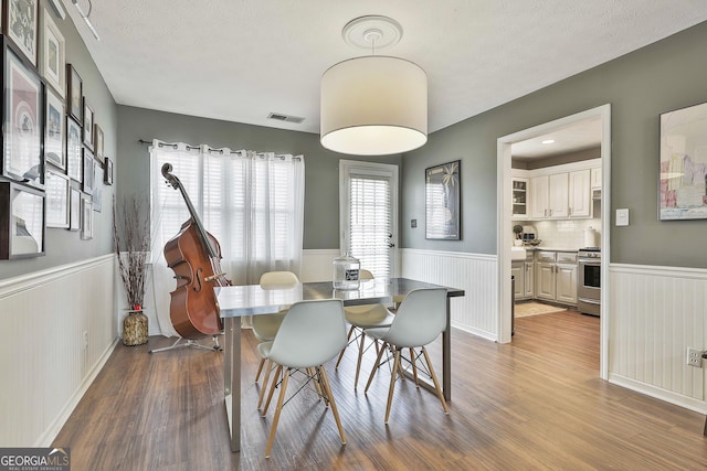 dining area featuring wainscoting, wood finished floors, and visible vents