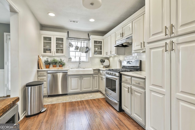 kitchen featuring light countertops, visible vents, appliances with stainless steel finishes, a sink, and under cabinet range hood