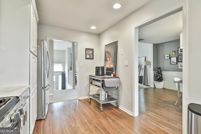 hallway with baseboards, light wood finished floors, visible vents, and recessed lighting