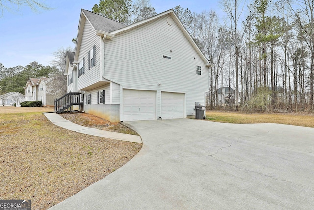 view of side of home with a garage, a yard, and driveway