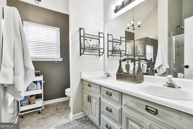 full bathroom with double vanity, toilet, an inviting chandelier, a sink, and a shower stall