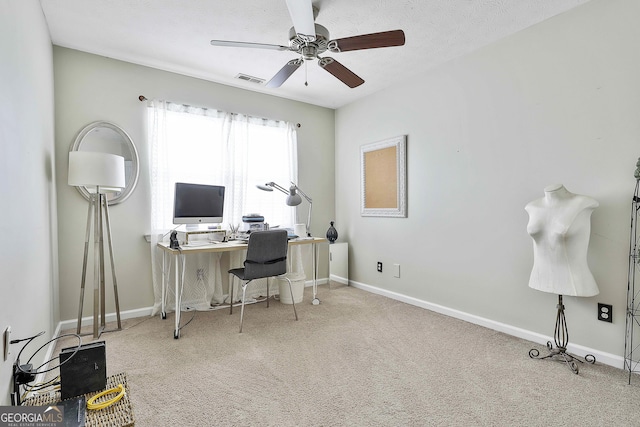 carpeted office space featuring a ceiling fan, visible vents, a textured ceiling, and baseboards