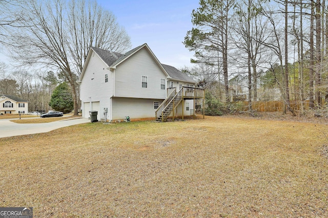 view of side of home featuring concrete driveway, a lawn, stairway, an attached garage, and a deck