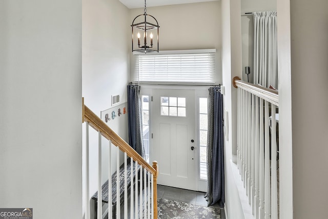 foyer with a chandelier, a high ceiling, stairs, and visible vents