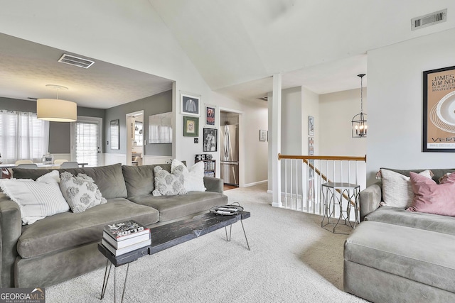 living room featuring high vaulted ceiling, carpet, visible vents, and a notable chandelier