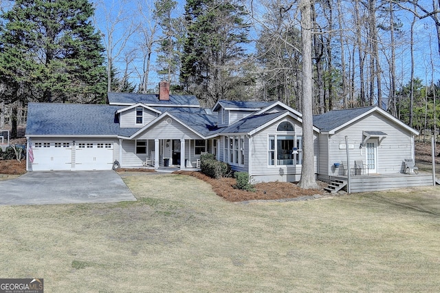 view of front of home with a front yard, driveway, a chimney, and an attached garage