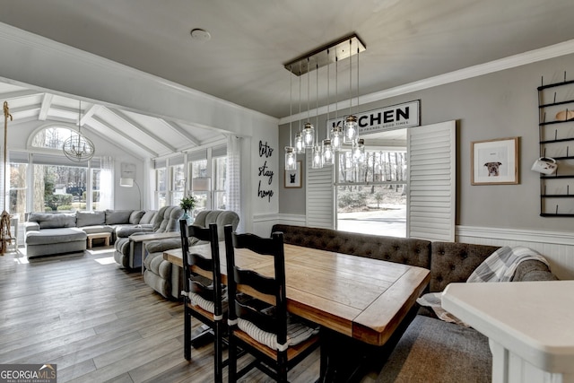 dining area featuring ornamental molding, wainscoting, lofted ceiling with beams, and wood finished floors