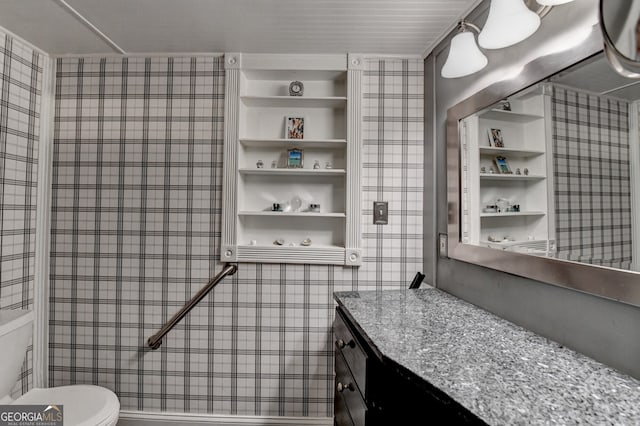 bathroom featuring toilet, built in shelves, vanity, and tile walls