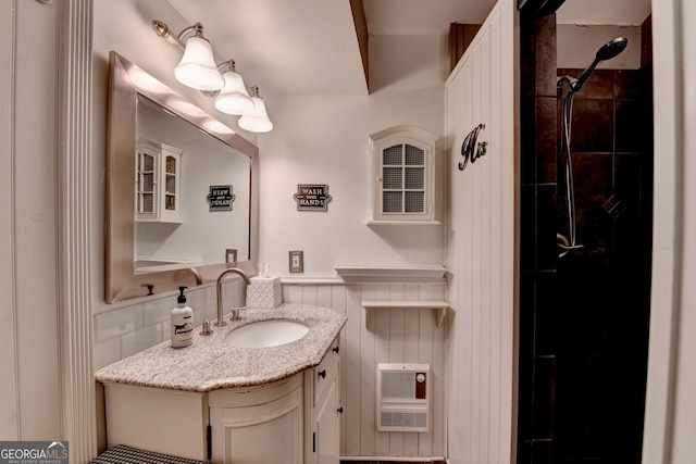 full bathroom featuring tiled shower, vanity, and heating unit