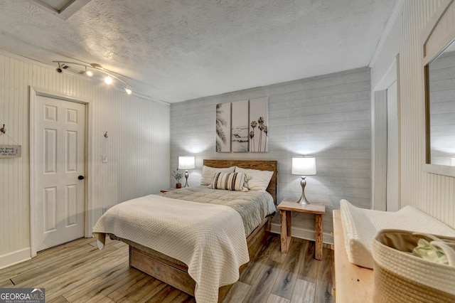 bedroom featuring light wood-style floors, a textured ceiling, and baseboards