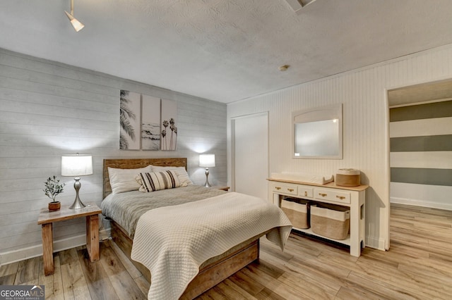 bedroom featuring baseboards, a textured ceiling, and light wood-style floors