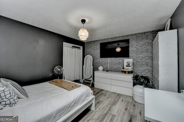 bedroom featuring brick wall and light wood-style flooring