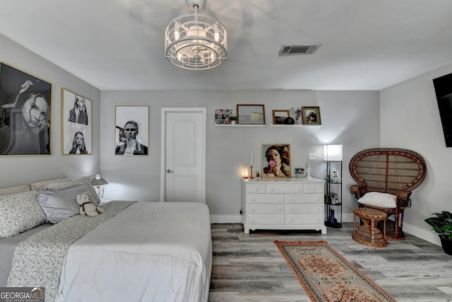 bedroom featuring baseboards, visible vents, an inviting chandelier, and wood finished floors