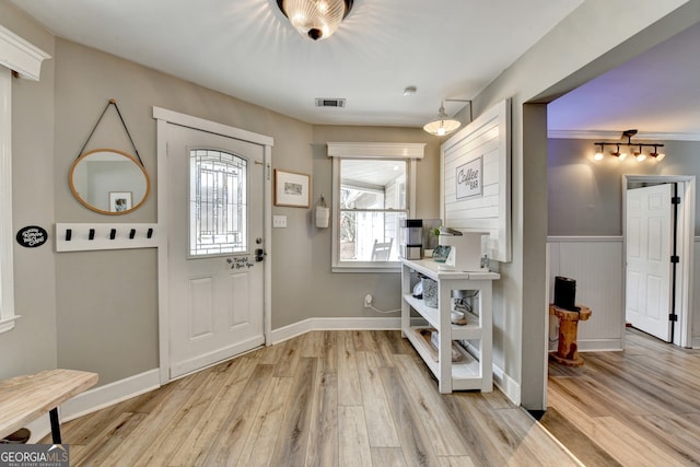 entryway with light wood-style floors, wainscoting, visible vents, and baseboards