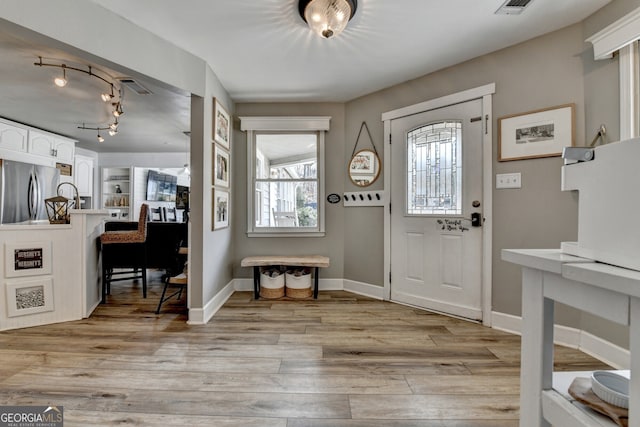 foyer featuring track lighting, light wood-style flooring, and baseboards