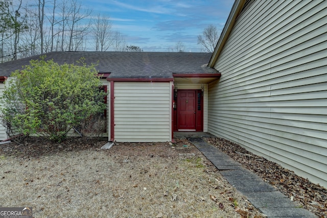 entrance to property featuring a shingled roof