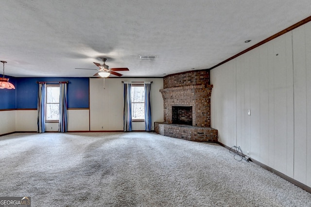 unfurnished living room with crown molding, visible vents, a brick fireplace, carpet flooring, and a textured ceiling