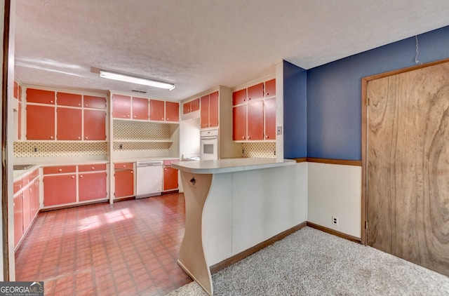 kitchen featuring tasteful backsplash, light countertops, a textured ceiling, white appliances, and a peninsula