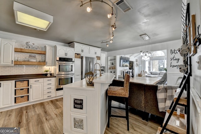 kitchen featuring visible vents, stainless steel appliances, light wood-type flooring, white cabinetry, and open shelves