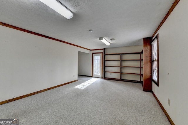 unfurnished room with a textured ceiling, ornamental molding, baseboards, and light colored carpet