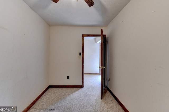 carpeted empty room featuring a ceiling fan and baseboards