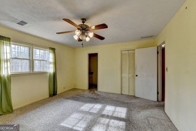 unfurnished bedroom with carpet, a closet, visible vents, and a textured ceiling