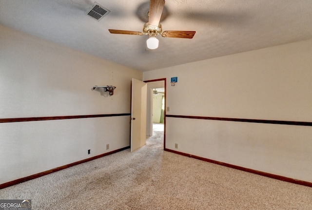 carpeted empty room with ceiling fan, visible vents, and baseboards