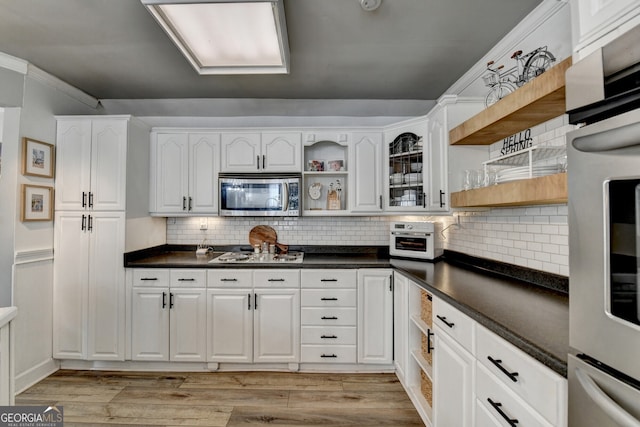 kitchen featuring stainless steel appliances, white cabinets, open shelves, light wood finished floors, and dark countertops