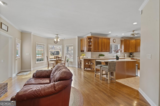 living room with baseboards, recessed lighting, light wood-style flooring, and crown molding