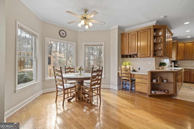 dining space featuring ornamental molding, built in desk, light wood-style flooring, and baseboards