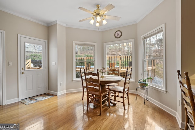 dining area with ornamental molding, light wood-style flooring, and baseboards