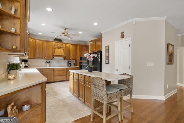 kitchen with a sink, light countertops, custom exhaust hood, black appliances, and crown molding