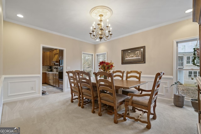 dining space featuring a healthy amount of sunlight, an inviting chandelier, ornamental molding, and light colored carpet